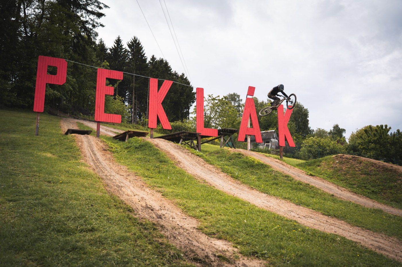 Jezdec ve výskoku nad skokem v bikeparku Peklák
